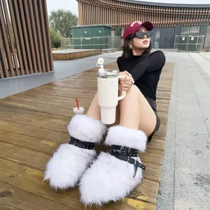Close-up view of white fluffy Y2K platform snow boots with black buckled rivet straps
