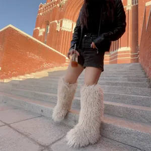 Outdoor lifestyle foto van vrouw die pluizige witte faux fur kniehoge laarzen draagt