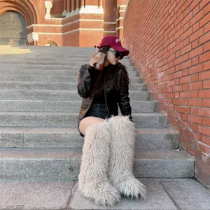 Stijlvolle vrouw met oversized harige imitatiebont kniehoge sneeuwlaarzen op een stenen trap