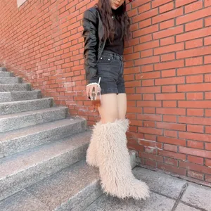 Detailweergave van beige kniehoge laarzen van imitatiebont bij een trendy outfit.