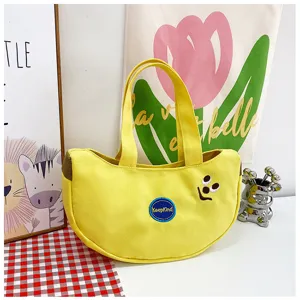 Nahaufnahme einer gelben Segeltuch-Tasche in Bananenform mit süßer Smile-Stickerei.