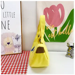 Seitenansicht einer süßen gelben Leinwand-Handtasche in Bananenform mit Stickerei.
