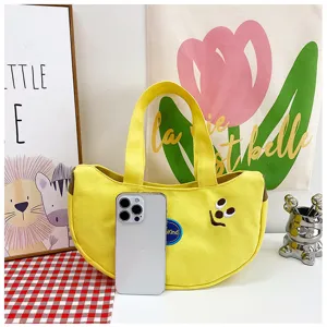 Detailansicht einer gelben Segeltuchtasche mit Bananenform und süßer Stickerei für Kinder