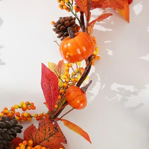 Detailed view of artificial autumn garland with decorative pumpkins, pine cones and leaves.
