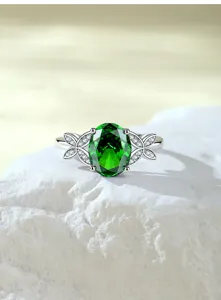 Gedetailleerde opname van een zilveren ring met ovale groene edelsteen en steentjes.