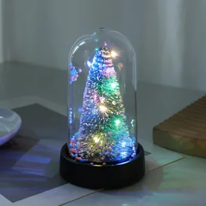 Vista dettagliata della lampada notturna albero di Natale luminosa sotto cupola in vetro.
