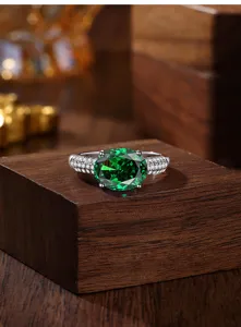 Close-up detail van zilveren groene edelsteen ring met fonkelende zirkonia op houtblok.