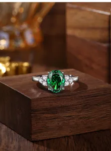 Gedetailleerde close-up van een elegante ovale groene smaragdring met schitterende stenen.