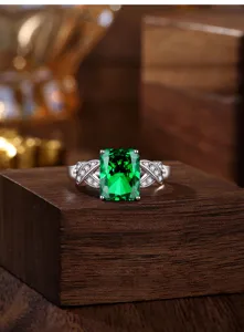 Prachtige zilveren ring met groene edelsteen in smaragdgeslepen vorm en glinsterende steentjes.