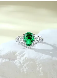 Close-up van de zilveren ring met peervormige groene edelsteen en gedetailleerde kroonband.