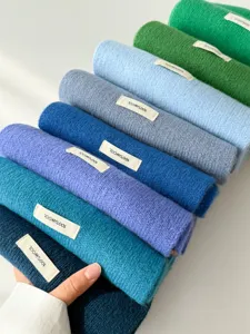 Detailed view of colorful 100% wool scarves rolled neatly in gradient shades for winter.