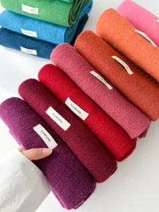 Detailed close-up view of multiple rolled colorful wool scarves neatly stacked together nicely.