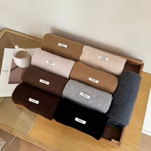Detail shot of rolled woolen scarves in multi colors placed neatly in a wooden tray.