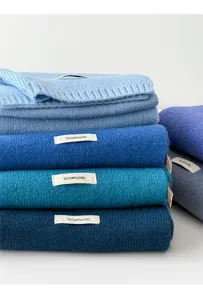 Detailed view of folded blue wool scarves featuring a 100% wool label, cozy winter detail.