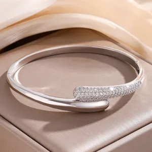 Stijlvolle C-vormige open armband met schitterende strass-steentjes en gladde metalen afwerking.