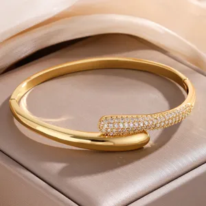 Vergulde C-vormige open armband met zirkonia pavé in detail op een elegante display doos getoond