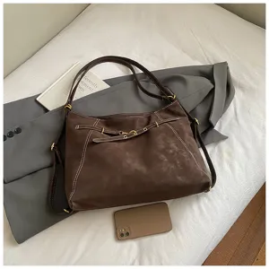 Brown vintage style shoulder bag detail, matte texture with white contrast stitching.