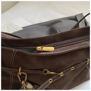 Close-up detail of dark brown retro shoulder tote bag with contrast stitching and metal hardware.