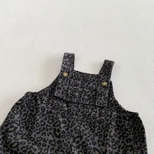 Infant leopard print overall detail, close-up of cute baby romper strap and front bib.