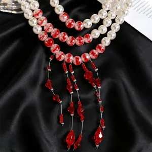 Macro shot of fashion pearl necklace featuring Y-shape red beaded tassels on black silk