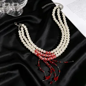 Close-up of elegant multi-strand pearl necklace with red tassel details on black satin