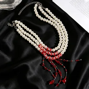 Close-up detail of a multi-layer white pearl necklace featuring vibrant red bead tassels