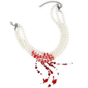 Detail view of an elegant three-layer white pearl necklace with red bead tassels.