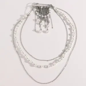 Detalle de cadena plateada multicapa con perlas y broche de borlas de estilo ins.