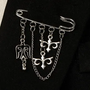 Detailed view of a silver-toned brooch with Kazakh ethnic motifs and dangling chains.