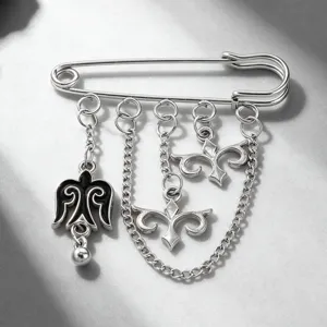Close-up of Kazakh-style silver safety pin brooch with ethnic charms and chains.