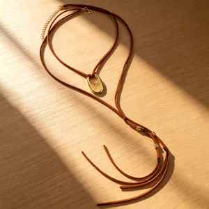 Nahaufnahme einer braunen Vintage-Wildlederkette mit einem polierten goldenen U-Anhänger.