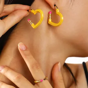 Detailansicht der kreativen gelben Herzohrringe in Bleistiftform und des passenden Rings
