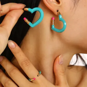 Nahaufnahme kreativer blauer Emaille-Bleistift-Herzohrringe und passendes Ring-Set