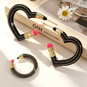 Kreative herzförmige Bleistift-Ohrringe und Ring mit schwarz-gold-rosa Emaille-Finish