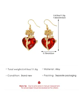 Vue rapprochée de boucles d'oreilles gothiques cœur avec rose dorée et pierre rouge.