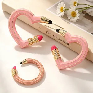 Detailansicht der kreativen pinkfarbenen Emaille-Ohrringe in Bleistift-Herzform mit Gold