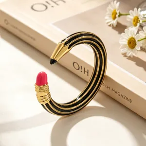 Nahaufnahme von kreativen bleistiftförmigen Emaille-Ohrringen mit Gold- und Schwarzstreifen.