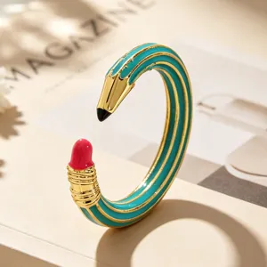 Detailansicht eines kreativen bleistiftförmigen Emaille-Ohrrings in Blaugrün und Gold.