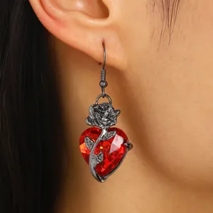 Détail en gros plan d'une boucle d'oreille gothique en cristal coeur rouge avec une rose noire
