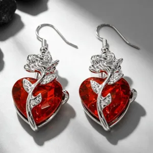 Détail de boucles d'oreilles gothiques cœur rouge avec rose argentée entrelacée.
