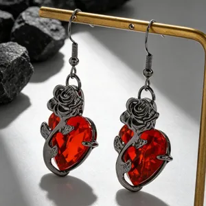 Gros plan de boucles d'oreilles gothiques avec rose noire et cœur rouge sur un présentoir