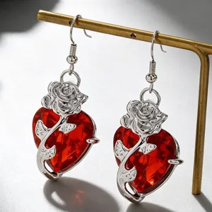 Gros plan de boucles d'oreilles cœur rouge gothique avec un motif de rose en argent