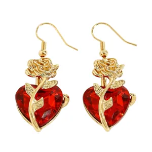 Vue détaillée de boucles d'oreilles rose dorée et cœur rouge facetté de style gothique