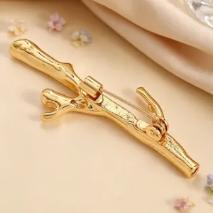 Close-up detail of a golden branch-shaped brooch with creative DIY flower holder design