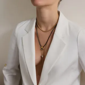 Eleganter mehrlagiger Goldschmuck mit Herzanhänger, präsentiert auf einem Blazer