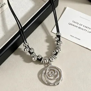 Detailed view of the silver spiral flower pendant with beads on a black cord necklace.