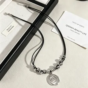 Detail of a silver vortex flower pendant necklace with black cord and metallic beads.
