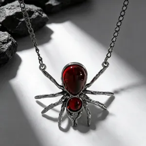Gros plan d'un collier araignée gothique avec des gemmes rouges et une chaîne sombre