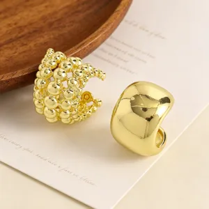 Detail view of two different gold-toned ear cuffs, one smooth and one beaded