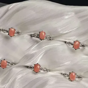 Detail view of multiple elegant silver-plated rings with oval rhodochrosite stones.